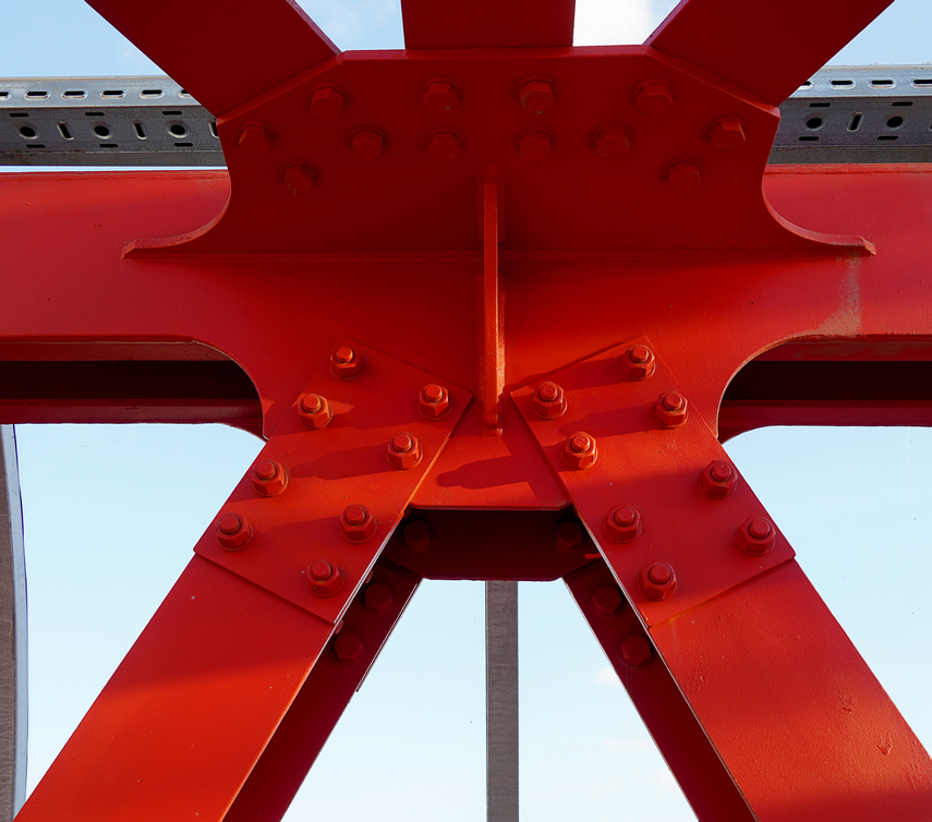 Red iron beams bolted. Asymmetrical connection of several iron beams in one place.